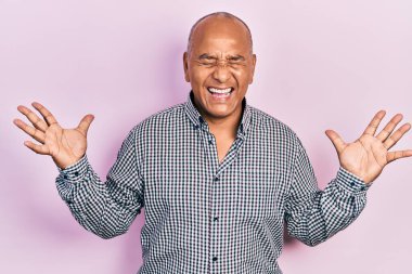 Orta yaşlı, gündelik kıyafetler giyen, çılgın ve çılgın başarıyı kutlayan, kollarını kaldırmış, gözlerini kapatmış heyecanlı çığlıklar atan Latin bir adam. Kazanan konsept 