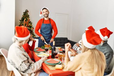 Mutlu bir şekilde gülümseyen bir grup genç adam evde servis etmek için kızarmış hindi kesiyor..