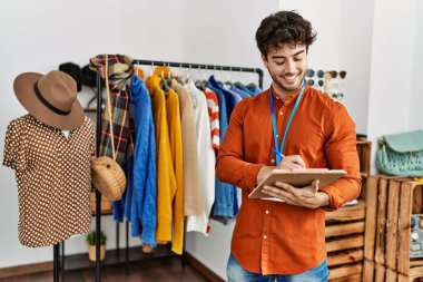 Genç İspanyol esnaf gülümsüyor. Giyim mağazasında çalışan panoya mutlu yazılar yazıyor..