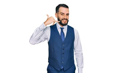 Sakallı, iş yeleği giyen, gülümseyen, el ve parmaklarıyla telefonla konuşan genç bir adam. iletişim kavramları. 