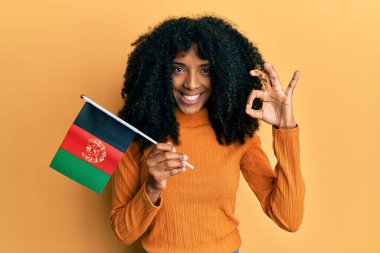 Afro saçlı Afro-Amerikan bir kadın. Afro bayrak taşıyor. Parmaklarıyla işaret veriyor. 
