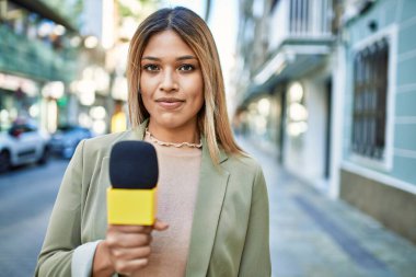 Sokakta mikrofon kullanan kendine güvenen genç Latin kadın.
