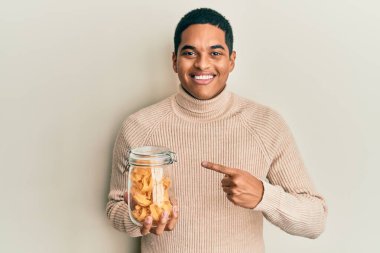 Genç, yakışıklı İspanyol adam elinde makarna kavanozuyla gülümsüyor. 