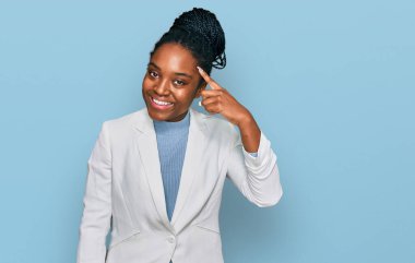 Genç Afro-Amerikan kadın iş kıyafetleri içinde gülümseyerek tek parmağıyla işaret ediyor, harika bir fikir ya da düşünce, iyi bir hafıza. 