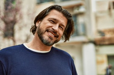 Kasabada gülümseyen orta yaşlı yakışıklı bir adam.