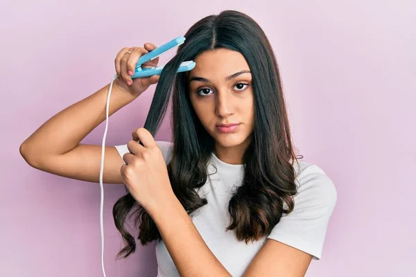 Young Hispanic Woman Holding Hair Straightener Skeptic Nervous Frowning Upset — Stock Photo, Image