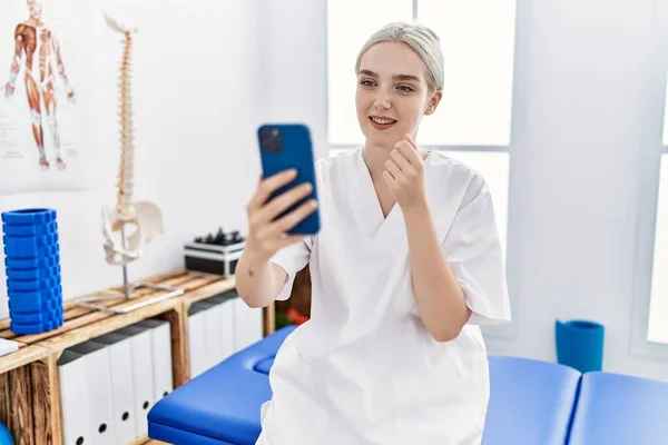 Young Caucasian Woman Wearing Physio Therapist Uniform Having Video Call — стоковое фото