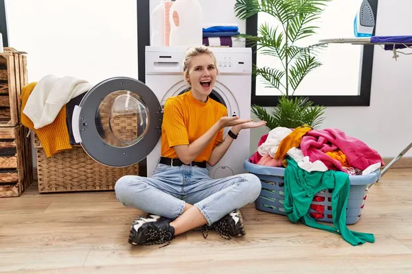 Ung Blond Kvinna Gör Tvätt Sitter Vid Tvättmaskin Pekar Sidan — Stockfoto