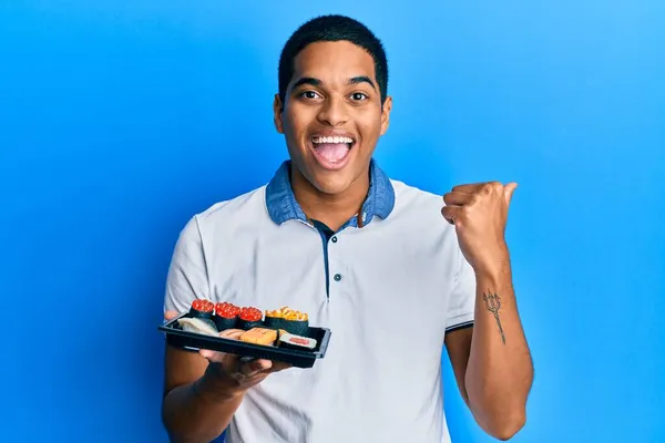 Joven Hombre Hispano Guapo Mostrando Plato Sushi Apuntando Con Pulgar — Foto de Stock