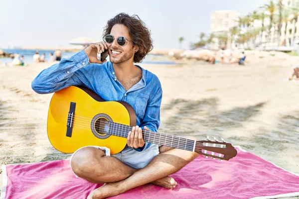 Jovem Hispânico Tocando Guitarra Falando Smartphone Sentado Areia Praia — Fotografia de Stock