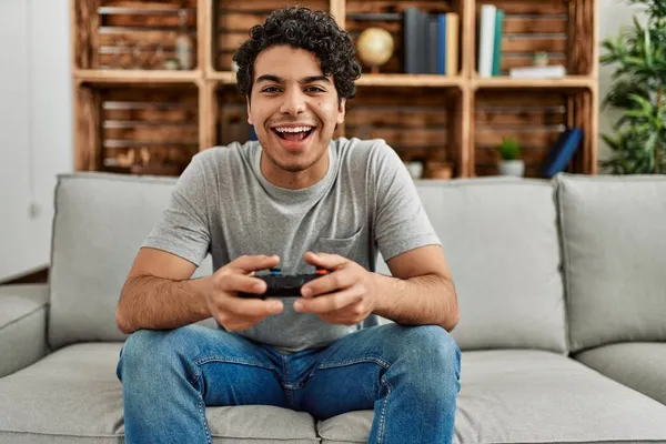 他的惊慌失措的年轻人坐在家里沙发上玩电子游戏 — 图库照片