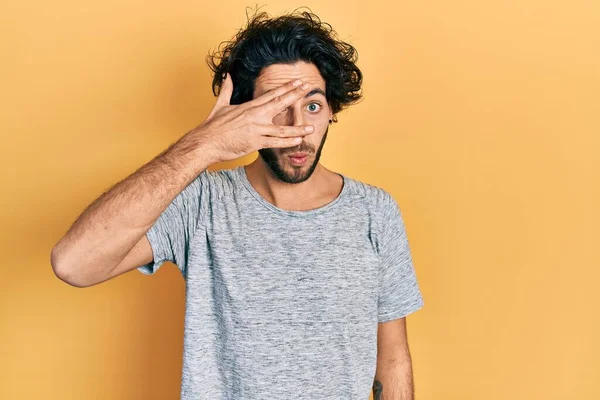 Pohledný Hispánec Neformální Šedé Tričku Vykukující Šoku Zakrývající Obličej Oči — Stock fotografie