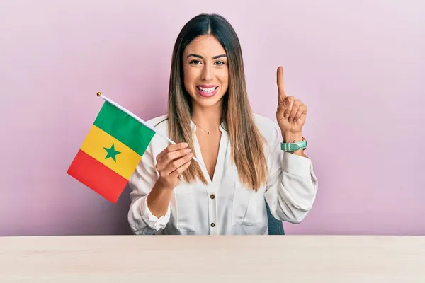 Jovem Hispânica Segurando Bandeira Senegal Sentada Mesa Sorrindo Com Uma — Fotografia de Stock