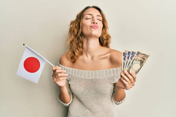 Молодая Белая Женщина Японским Флагом Банкнотами Смотрящая Камеру Дуя Поцелуй — стоковое фото