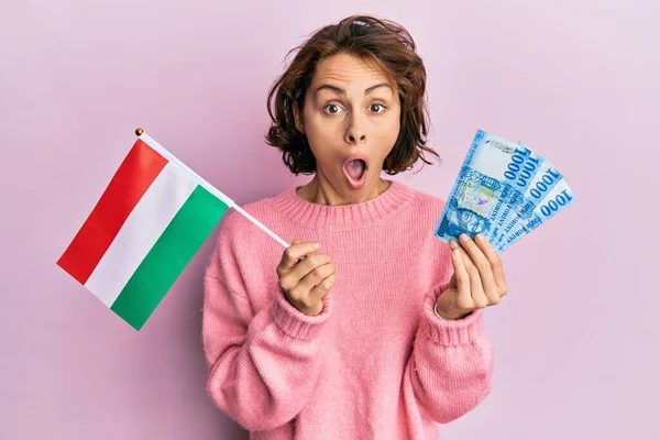 Młoda Brunetka Węgierską Flagą Forintami Banknotów Przerażona Zszokowana Zaskakującą Ekspresją — Zdjęcie stockowe