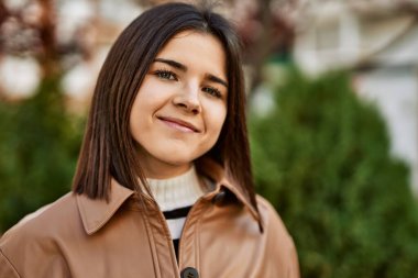 Genç, güzel, esmer kadın dışarıda mutlu bir şekilde gülümsüyor.