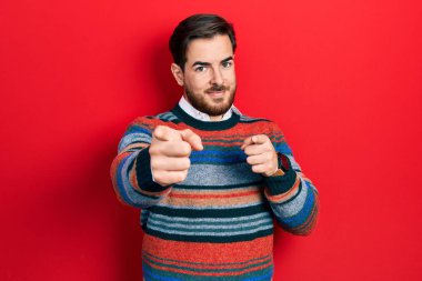 Zarif yün kazak giyen sakallı yakışıklı beyaz adam mutlu ve komik yüzüyle kamerayı işaret ediyor. iyi enerji ve titreşimler. 