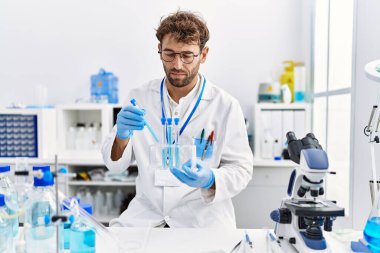 Laboratuvarda çalışan, bilim adamı üniforması giyen İspanyol genç adam.