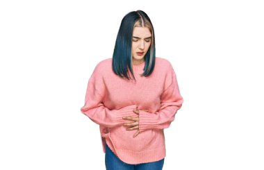 Genç, modern bir kız, midesi üstünde pembe yün bir kazak giyiyor. Çünkü hazımsızlık, acı verici bir hastalık ve kendini iyi hissetmiyor. Ağrı kavramı. 