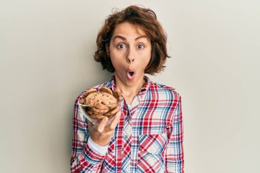 Çikolata parçacıklı kurabiyeler tutan genç esmer kadın ağzı açık kalmış, korkmuş ve hayrete düşmüştü. 