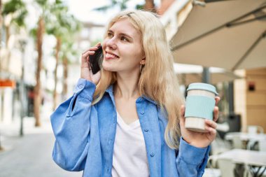Genç sarışın kadın güneşli bir günde telefonda konuşuyor.