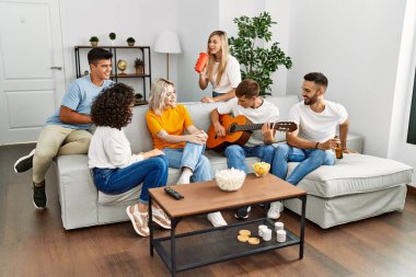 Partide gülümseyen ve evde klasik gitar çalan bir grup genç arkadaş..