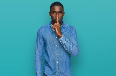 Gündelik giysiler giymiş genç Afro-Amerikan bir adam sessiz olmak istiyor. sessizlik ve gizli konsept. 