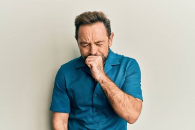 Sıradan kıyafetler giyen orta yaşlı bir adam kendini iyi hissetmiyor ve soğuk algınlığı veya bronşitin belirtisi olarak öksürüyor. sağlık hizmeti kavramı. 