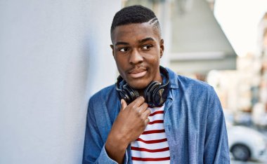 Şehirde kulaklık kullanan, ciddi bir suratı olan Afrikalı genç bir Amerikalı..