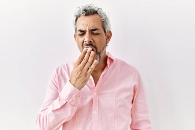 Orta yaşlı İspanyol bir adam izole edilmiş arka planda dikiliyor. Elle ağzını kapatmaktan sıkılmış. Huzursuz ve uykulu.. 
