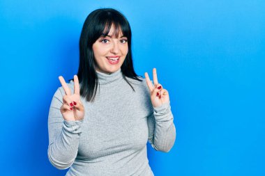 Gündelik kıyafetler giyen genç İspanyol kadın kameraya bakıp zafer işareti yapıyor. İki numara.. 