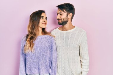 Gündelik kıyafetler giyen genç İspanyol çift gülümseyip yan tarafa bakıyor ve düşünüyor.. 