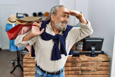 Butik dükkanında alışveriş torbaları tutan yakışıklı bir adam. Çok mutlu ve tebessüm ediyor. Çok uzaklara bakıyor. arama kavramı. 