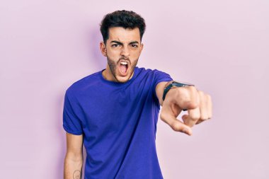Gündelik tişört giyen genç İspanyol adam kameraya kızgın ve sinirli bir şekilde seni işaret ediyor. 