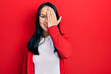 Güzel İspanyol bir kadın, burun piercingli, sıradan bir görünüm takıyor ve gözlük takıyor, bir gözünü eliyle kapatıyor, yüzünde kendine güvenen bir gülümseme ve şaşırtıcı bir duygu var.. 