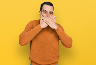 Kış süveteri giyen sakallı genç adam yanlışlıkla elleriyle ağzını kapatırken şok oldu. gizli kavram. 