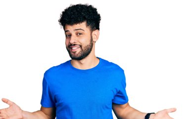 Mavi tişörtlü, sakallı genç Arap adam avuçlarını açıp gülümsüyor. Karşılaştırma ve reklam karşılaştırması yapıyor ve dengeyi sağlıyor. 