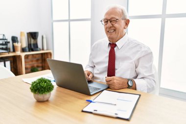 Ofiste çalışan son sınıf öğrencisi bilgisayarla göz kırpıyor kameraya seksi bir ifadeyle bakıyor, neşeli ve mutlu bir yüz ifadesi var.. 