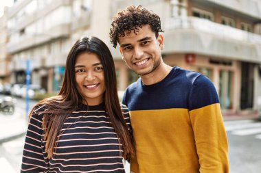 Genç Latin çift gülümsüyor ve şehirde sarılıyorlar..