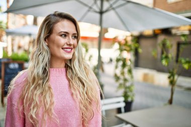 Genç sarışın kadın şehre gülümsüyor.