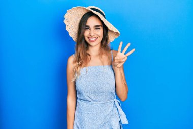 Yaz şapkası takan genç İspanyol kız gülümseyerek kendinden emin ve mutlu gülümserken üç numarayı işaret ediyor.. 