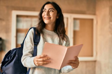 Genç ortadoğu öğrencisi kız şehirde mutlu bir şekilde kitap okuyor..