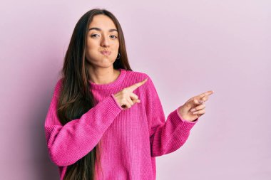 Genç İspanyol kız parmaklarını yandan göstererek komik yüzlü yanakları şişiriyor. Ağzı havayla şişer, havayı yakalar.. 