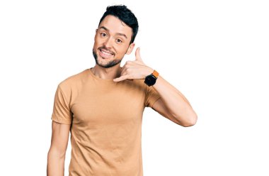 Sakallı, sıradan tişörtlü, gülümseyen, el ve parmaklarıyla telefonla konuşan İspanyol bir adam. iletişim kavramları. 