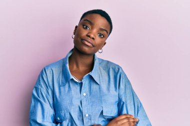 Sıradan kıyafetler giyen genç Afro-Amerikan kadın yüzünde ciddi bir ifadeyle rahatladı. Basit ve doğal bir şekilde kameraya bakıyorsun.. 