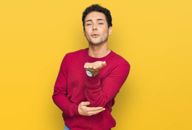 Gündelik kıyafetler giymiş genç yakışıklı bir adam kameraya bakıyor ve havada bir öpücük savuruyor. Güzel ve seksi. aşk ifadesi. 