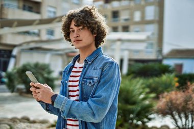 Genç İspanyol adam şehirde akıllı telefon kullanıyor.