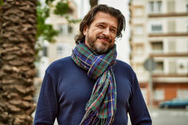 Parkta gülümseyen orta yaşlı yakışıklı adam.