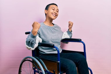 Tekerlekli sandalyede oturan çok mutlu ve heyecanlı İspanyol bir kadın kolları havada, gülümseyen ve başarı için bağıran bir jest yapıyor. kutlama konsepti. 