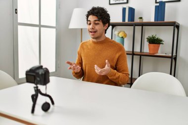 Evdeki kanepede oturan Latin asıllı genç bir adam kamerayla görüntülü görüşme yapıyor..